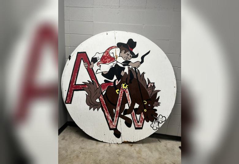 An approximately six feet in diameter round wooden sign with a while background, the Westerner logo, and the letters A and W in red.