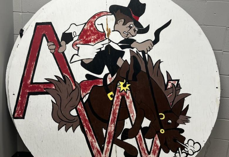 An approximately six feet in diameter round wooden sign with a while background, the Westerner logo, and the letters A and W in red.